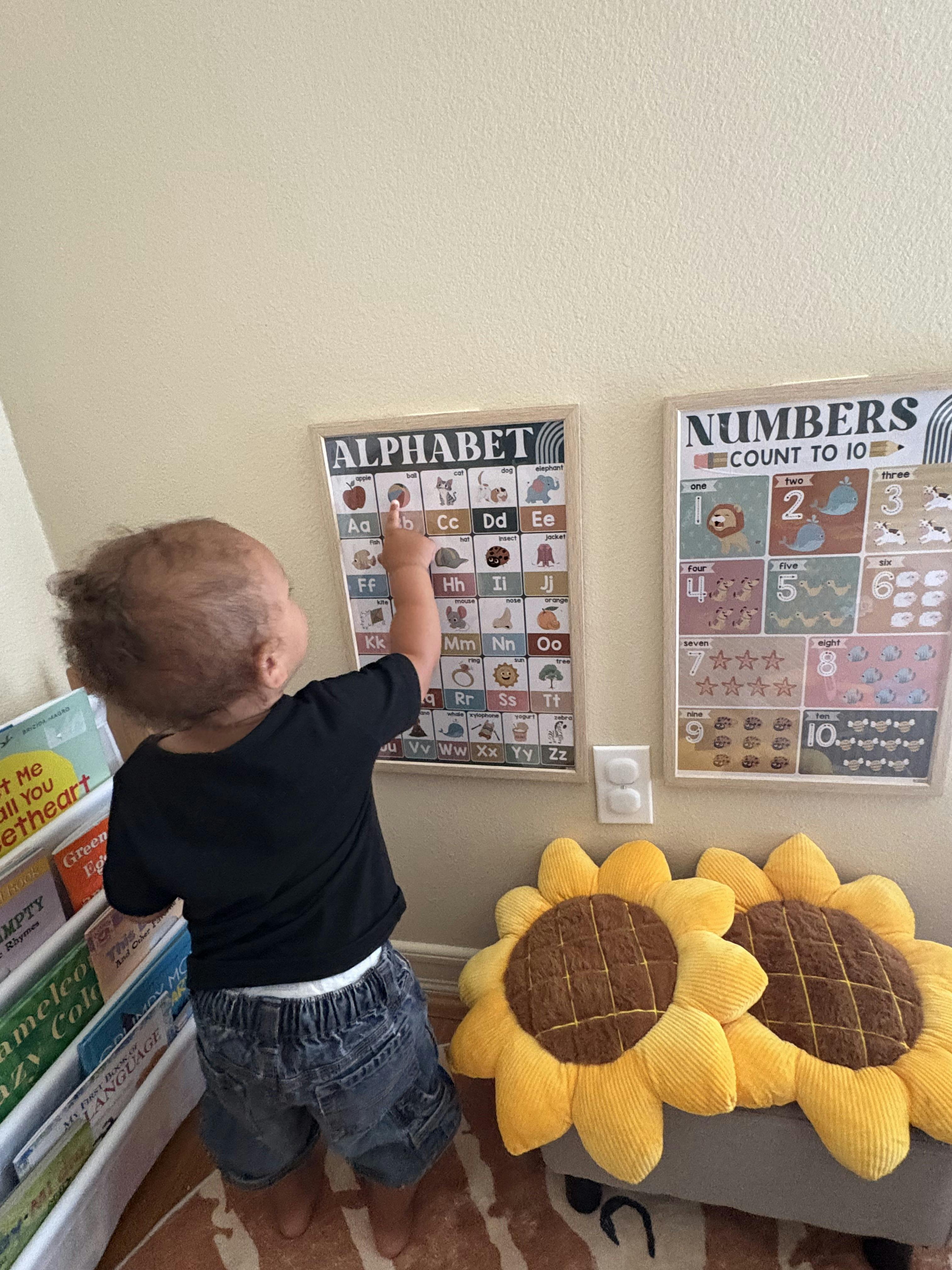 Child pointing at an alphabet chart on a wall