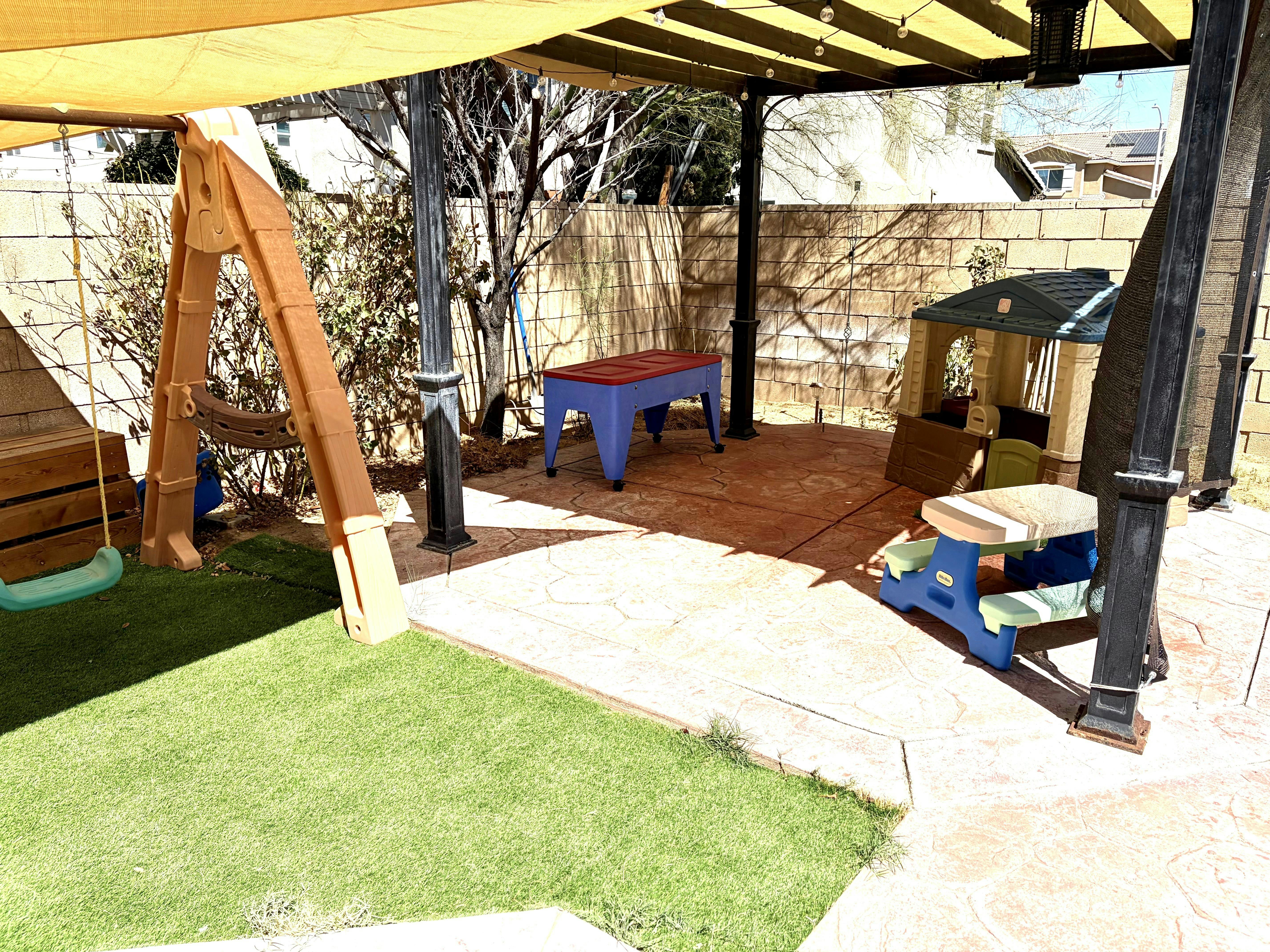 Playground equipment for children on a patio under a canopy