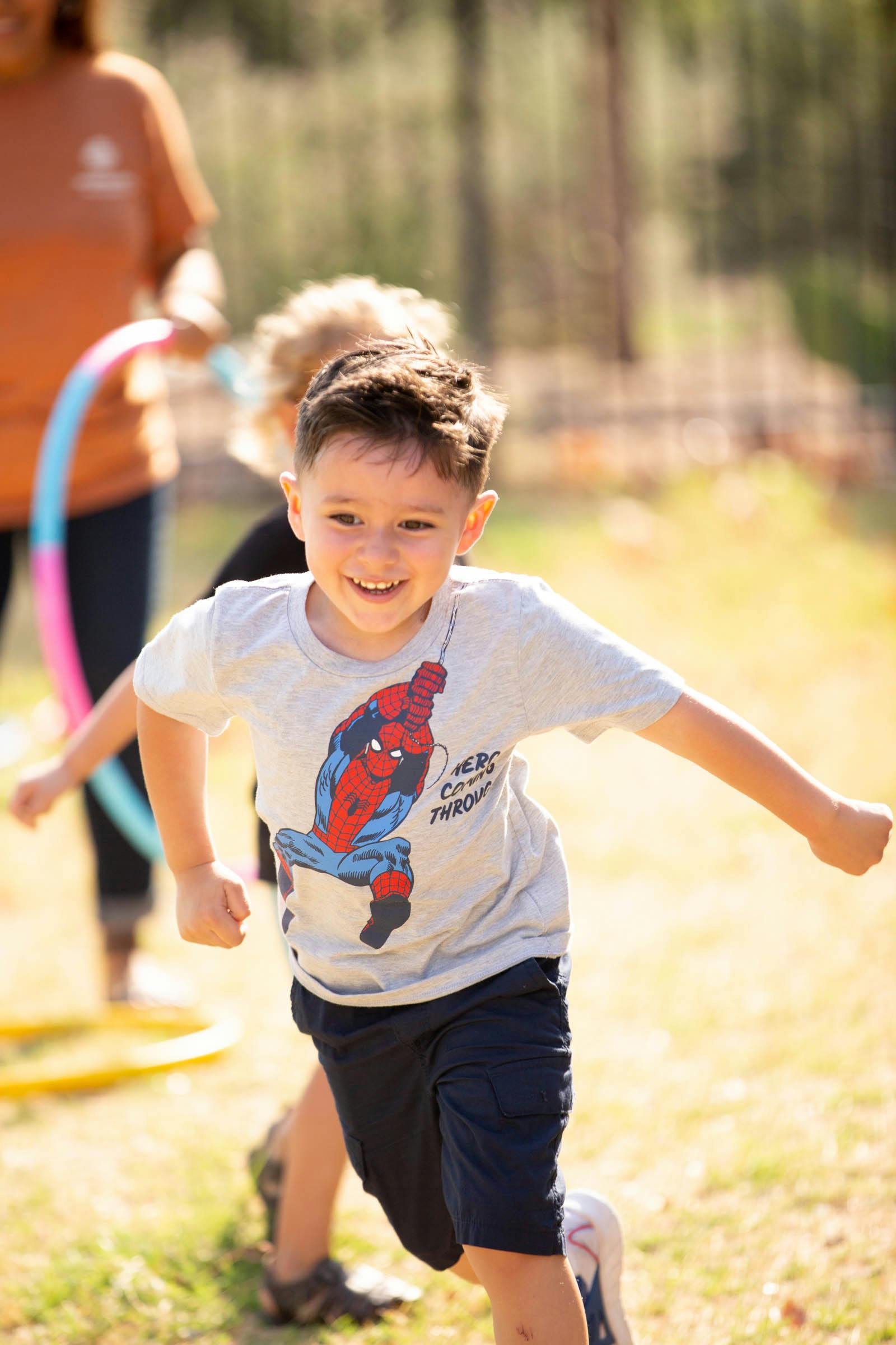 Child in a Spider-Man shirt running outdoors