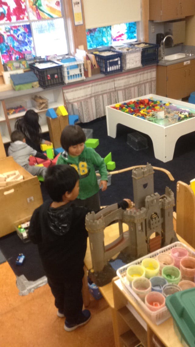 Two children playing with a toy castle in a classroom