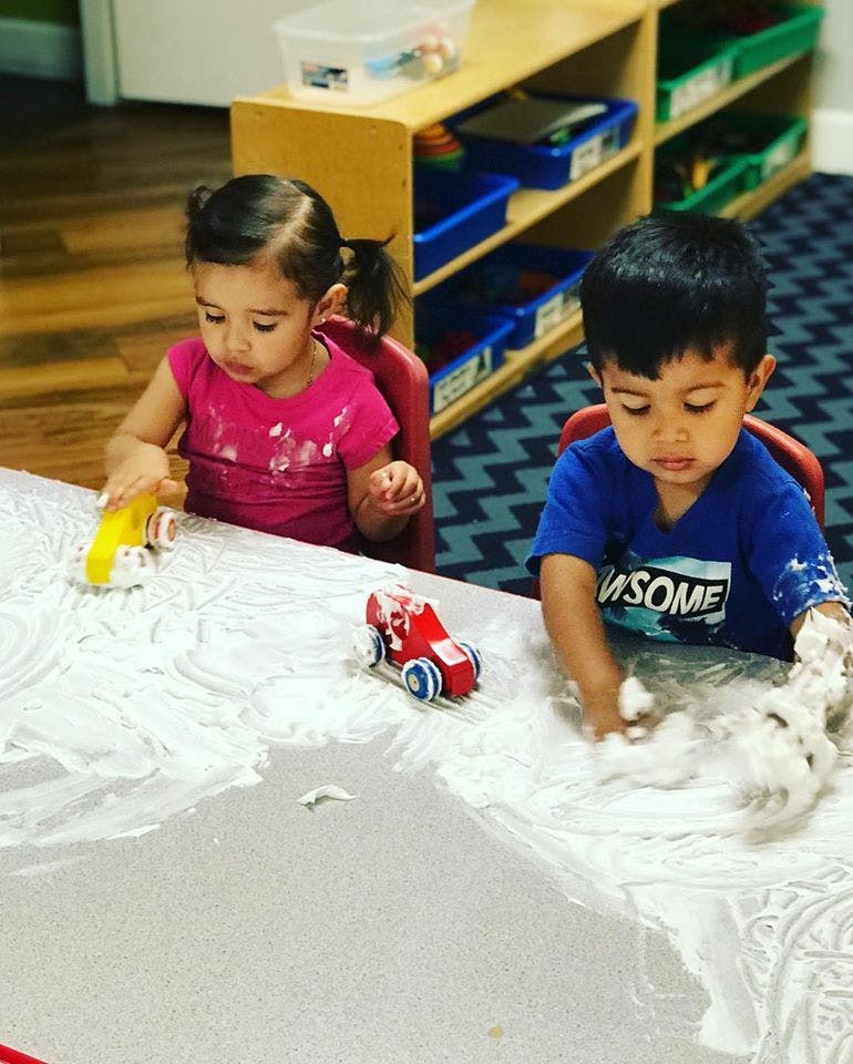 Two children playing with cars and foam on a table