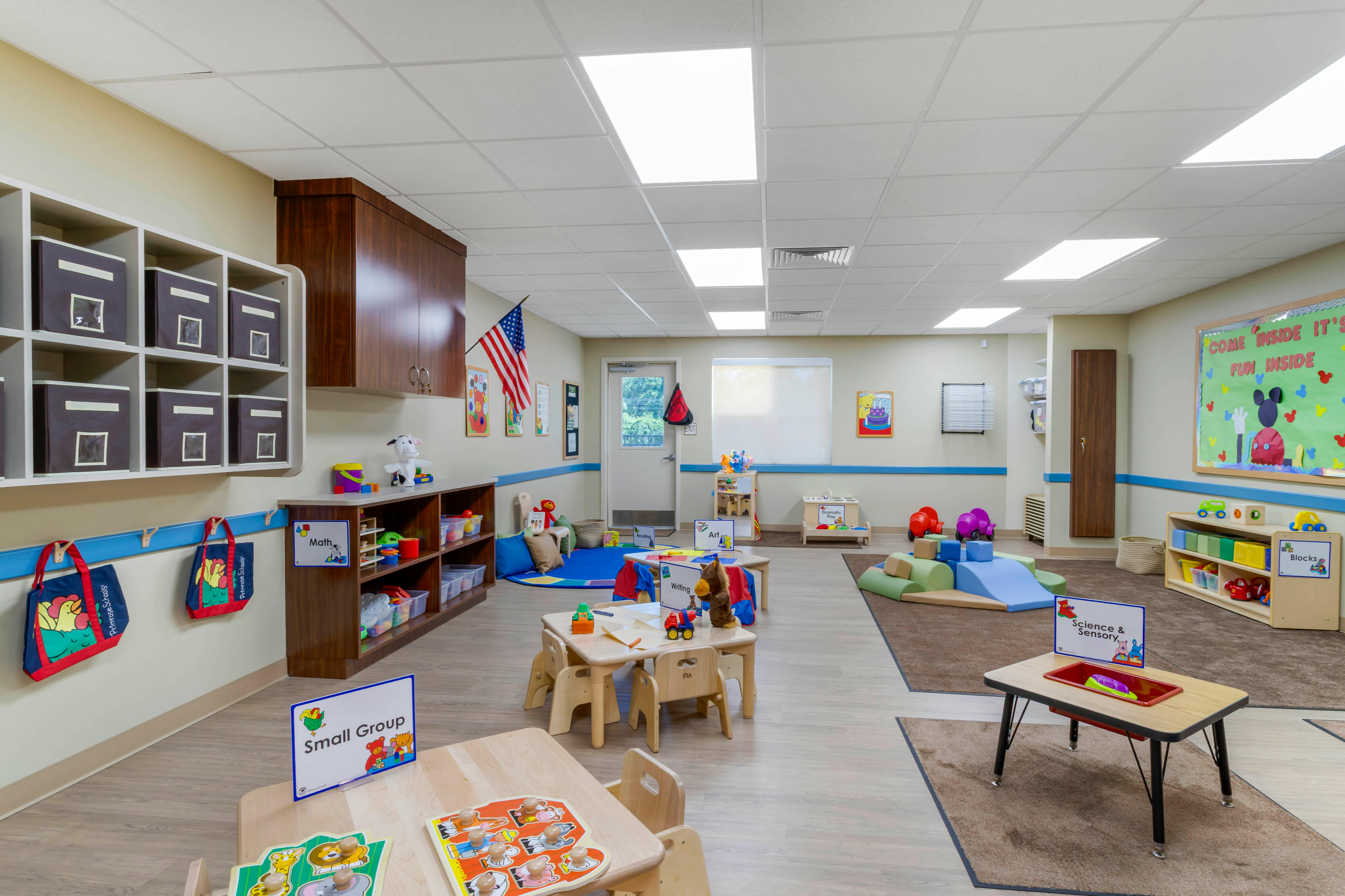 Colorful preschool classroom with various activity stations and small tables