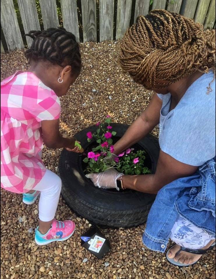 Person and child planting flowers in a tire