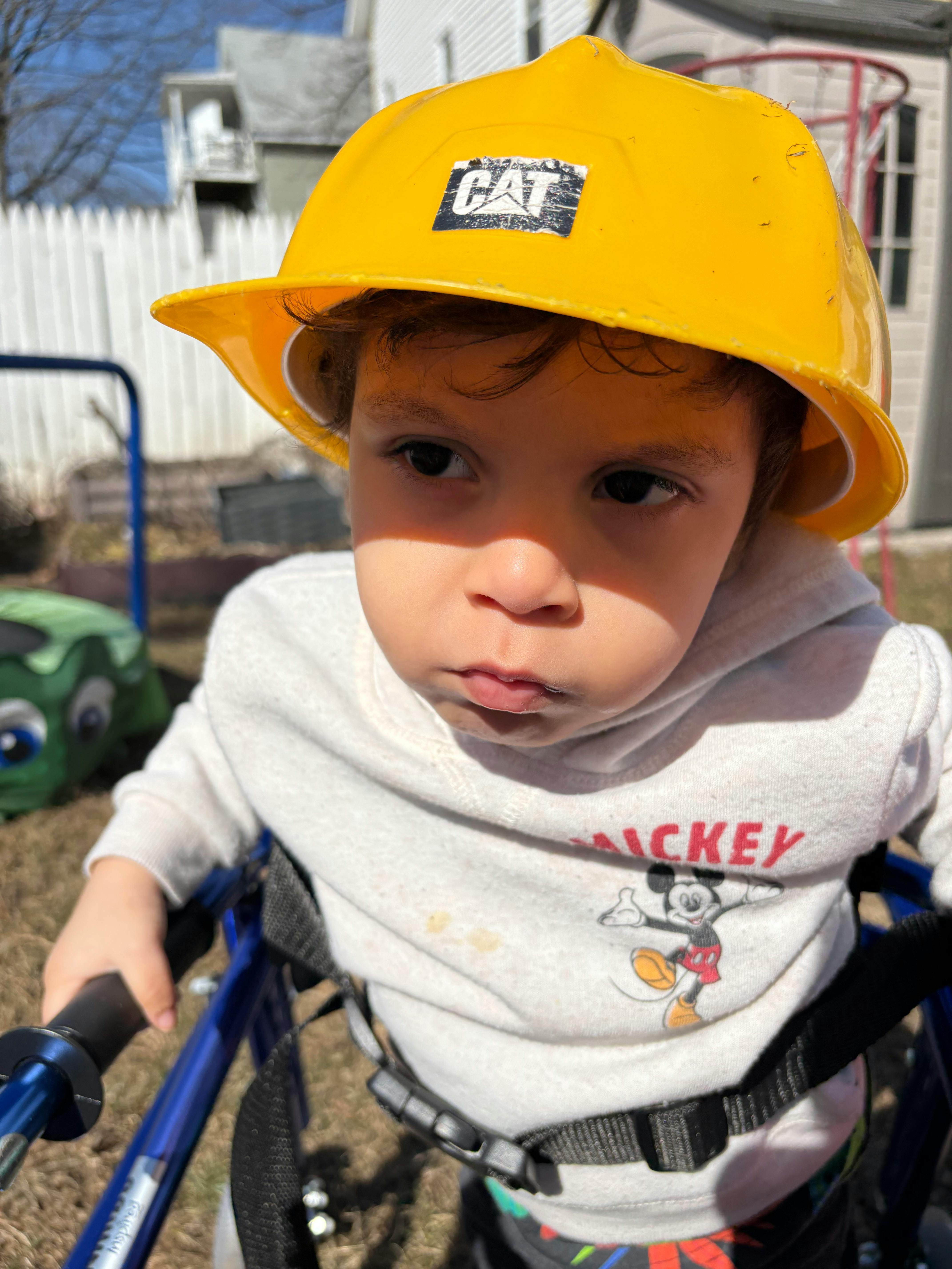 Child in a yellow hard hat and a walker