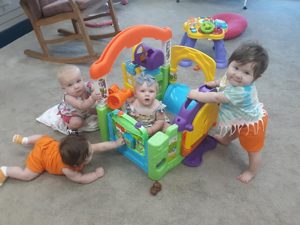 Four children playing with a colorful activity center