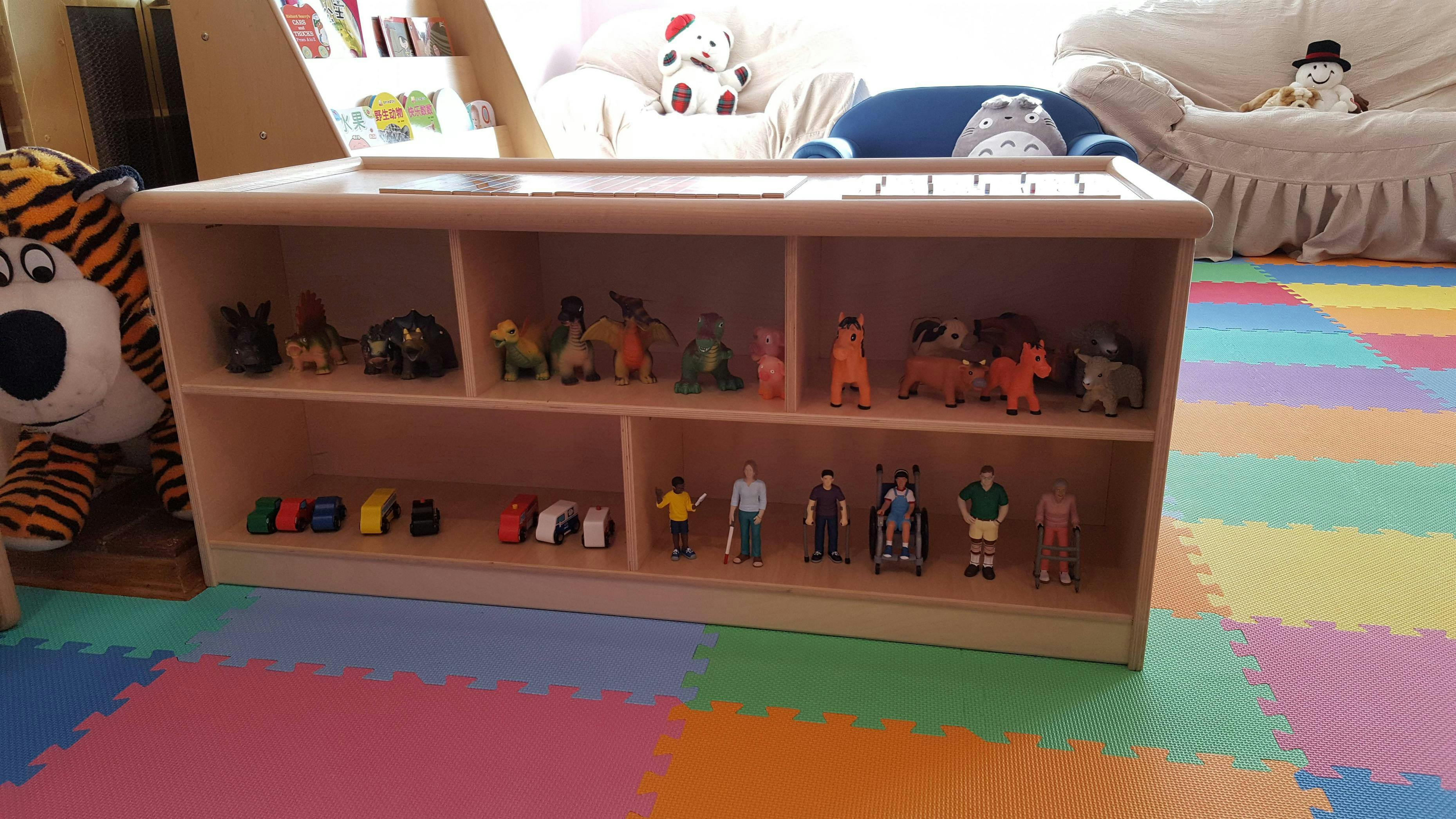 Wooden shelf with toys including animal figures, cars, and people figures
