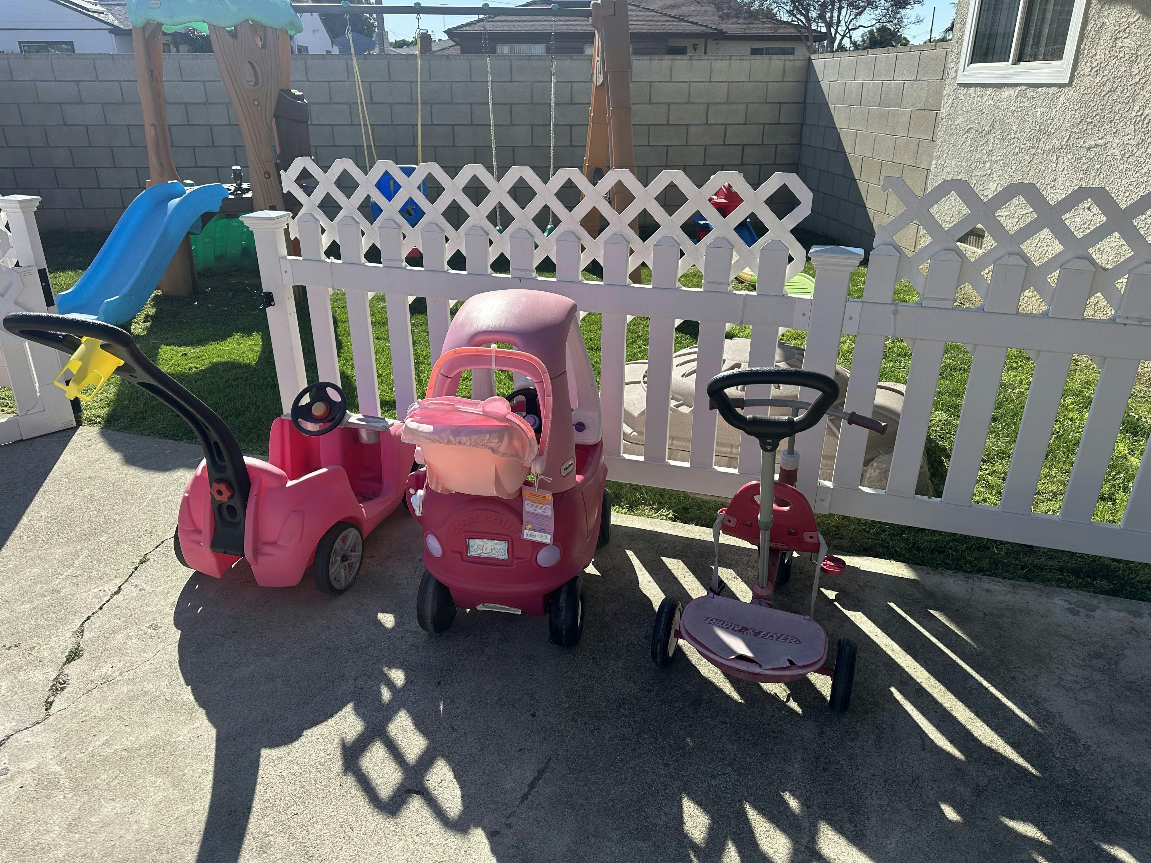 Pink toy car, push car, and scooter on a concrete patio