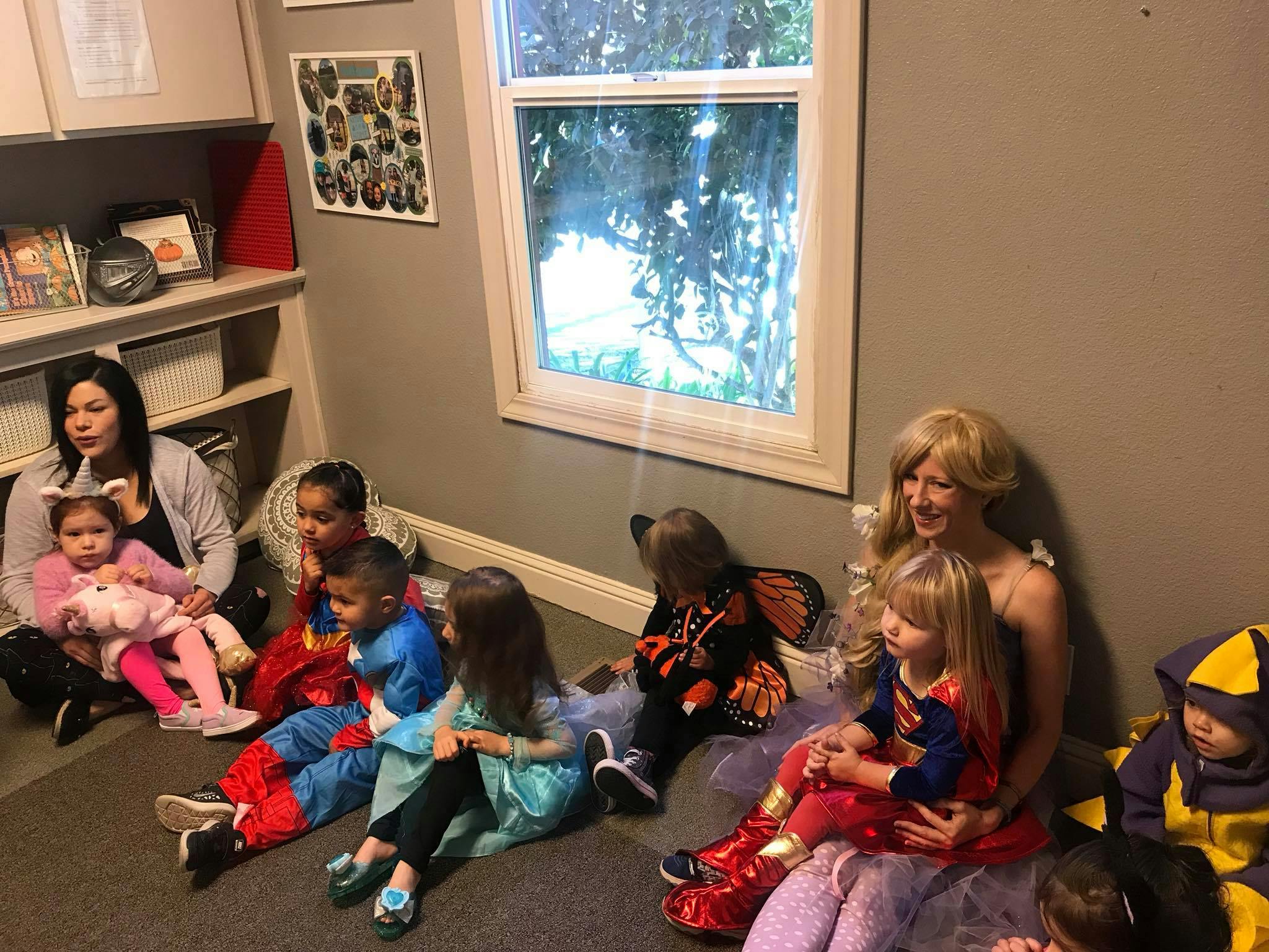Adults and children in costumes sitting on the floor