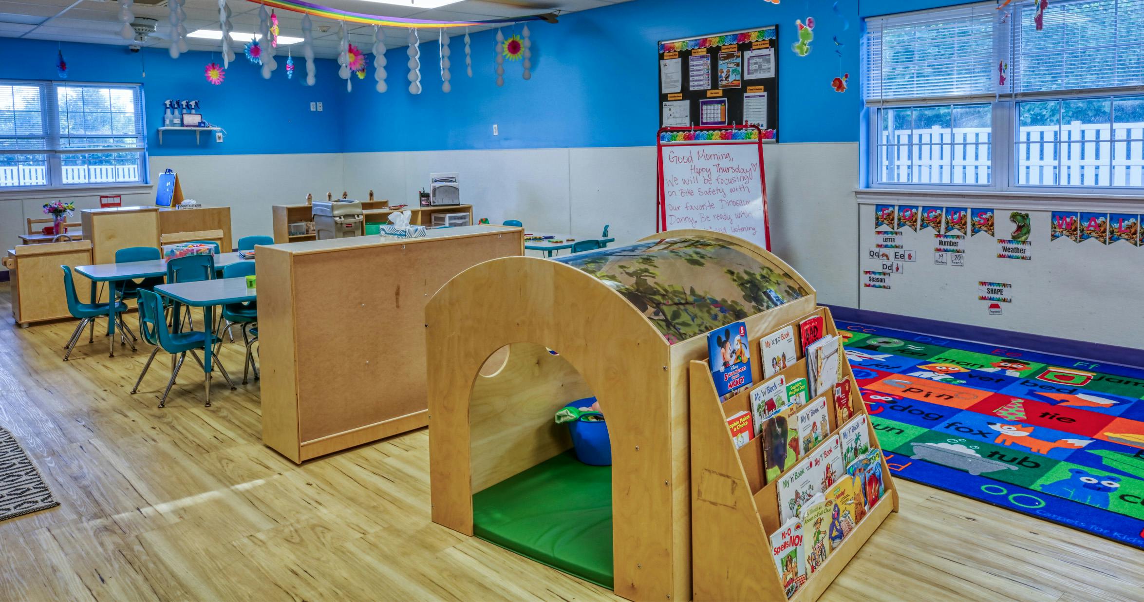 Classroom with small tables, chairs, and a play structure