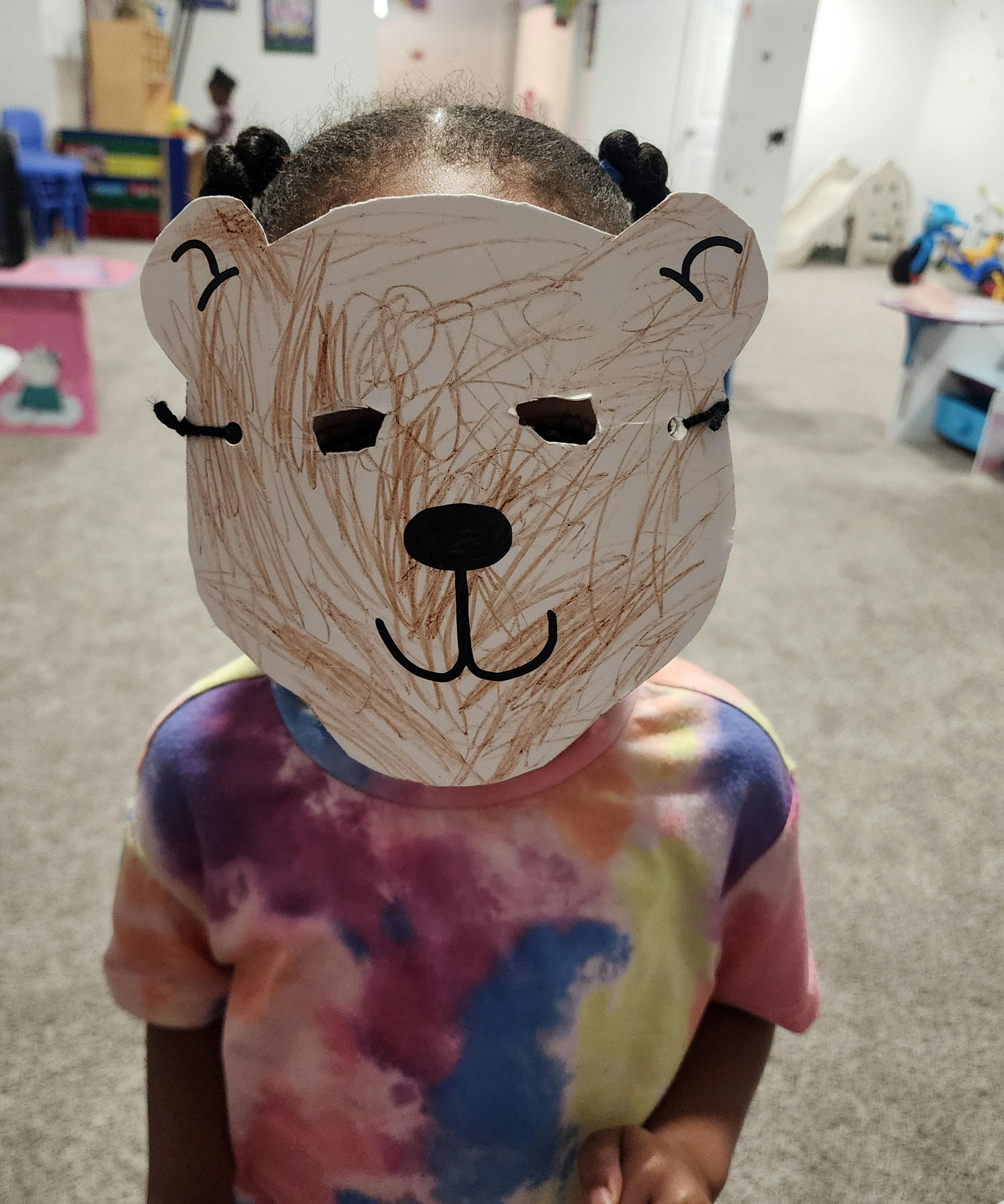 Child wearing a bear mask and a tie-dye shirt