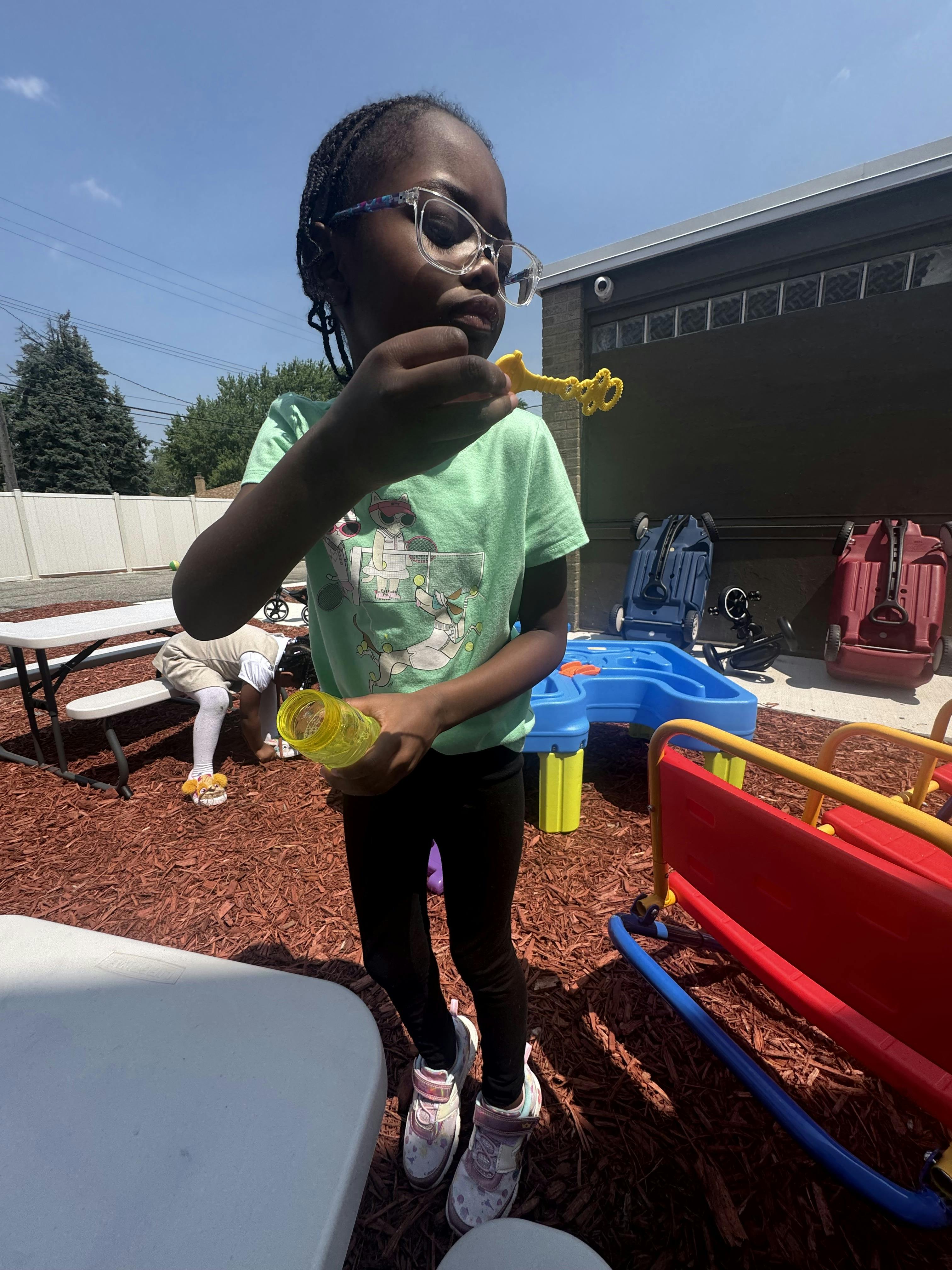 Child in glasses blowing bubbles outdoors