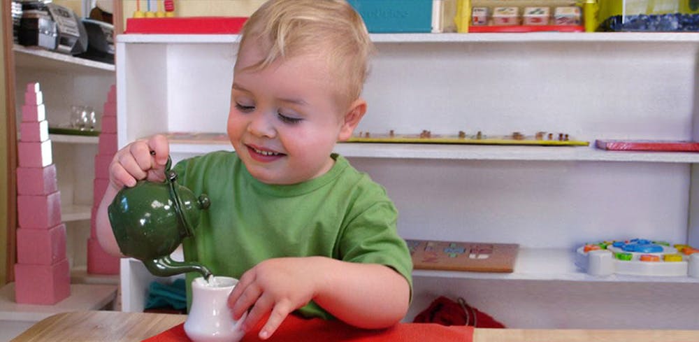 Child pouring from a small teapot into a cup