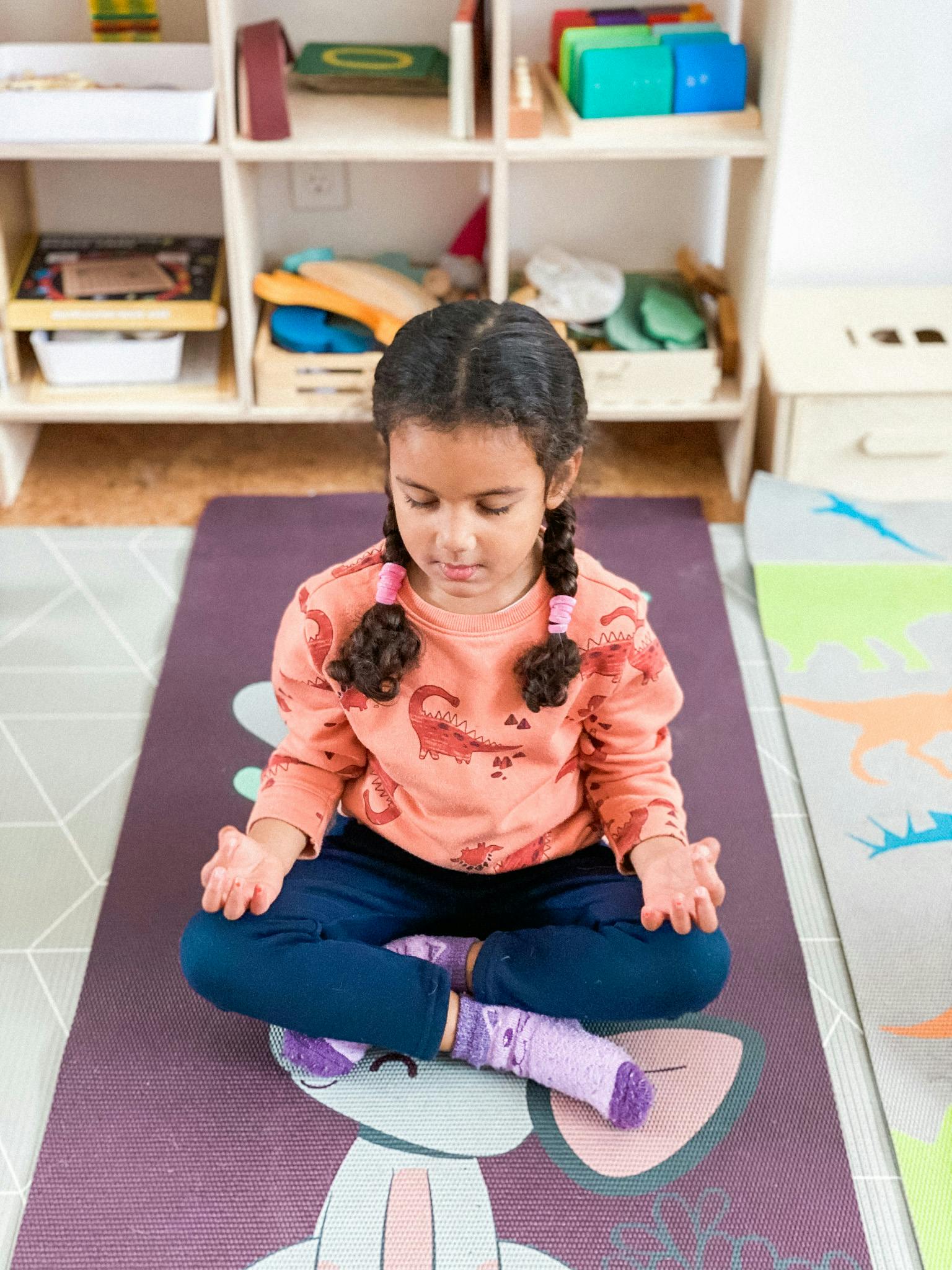 Child sitting cross-legged on a yoga mat