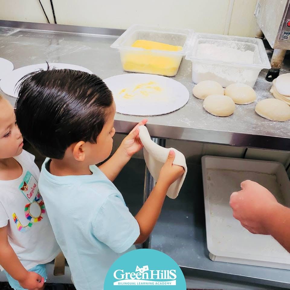 Child stretching dough in a kitchen