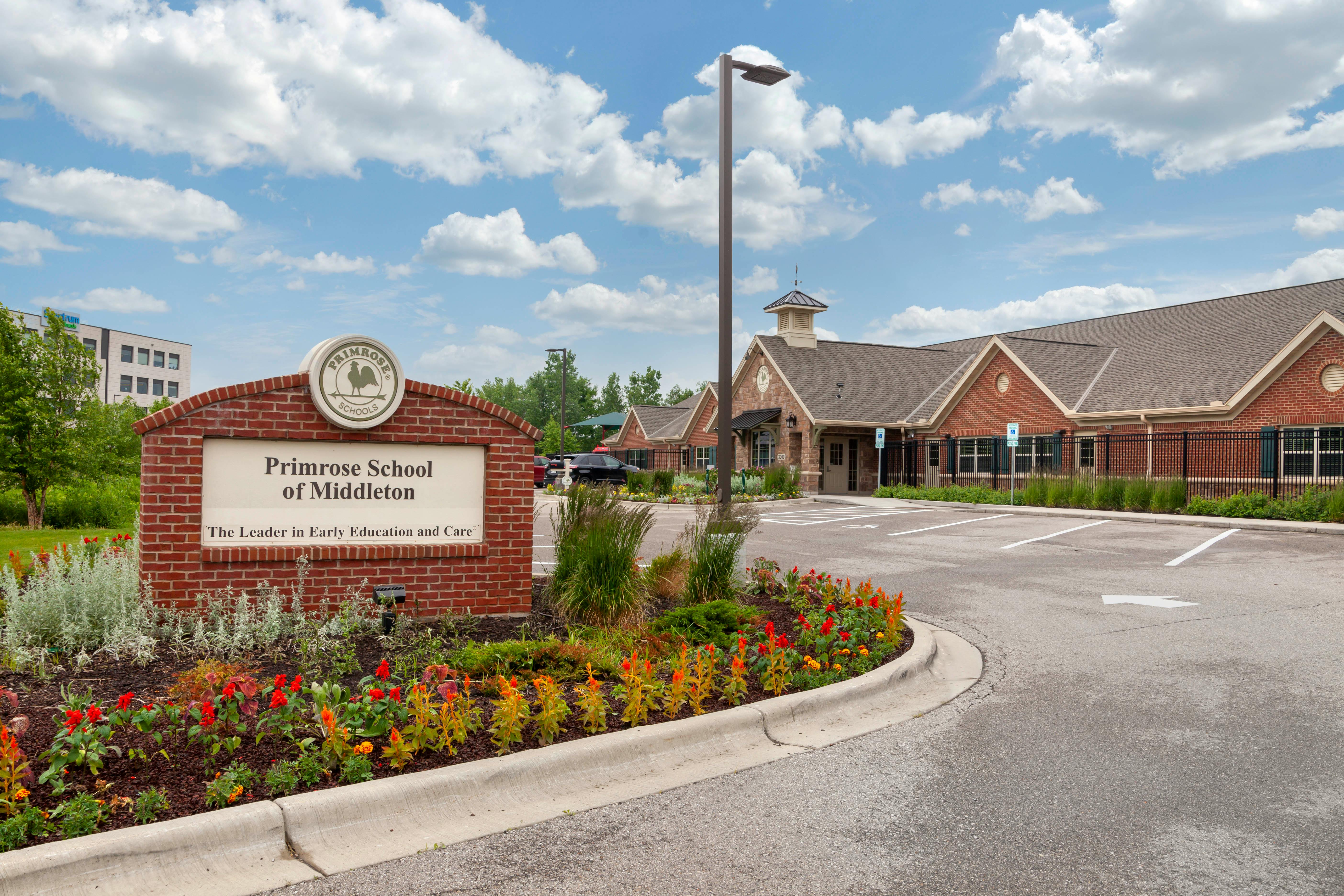 Brick school sign with Primrose School of Middleton text next to a building