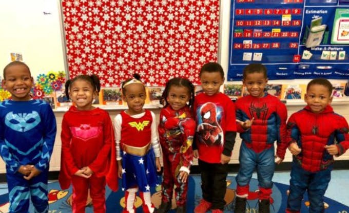 Six children in superhero costumes standing in a row