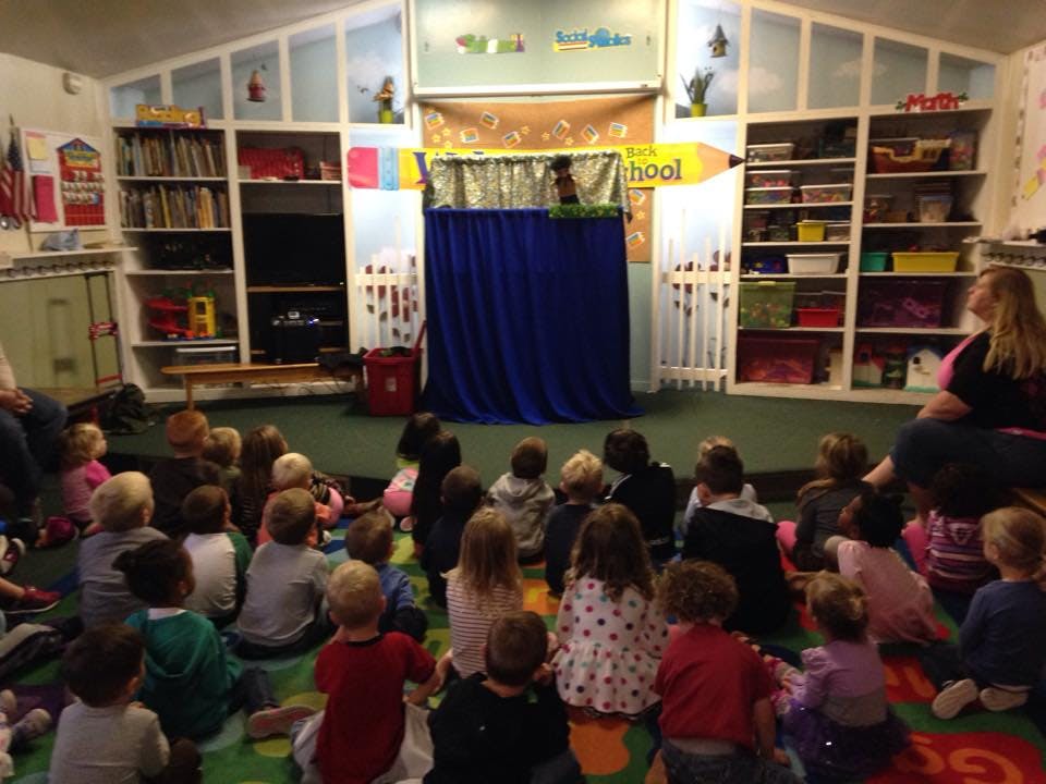 Children sitting on the floor watching a puppet show