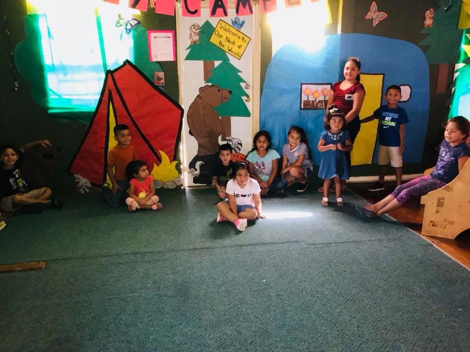 Group of children and an adult in a classroom with camp-themed decorations
