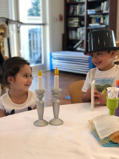 Two children at a table with two decorative candlesticks