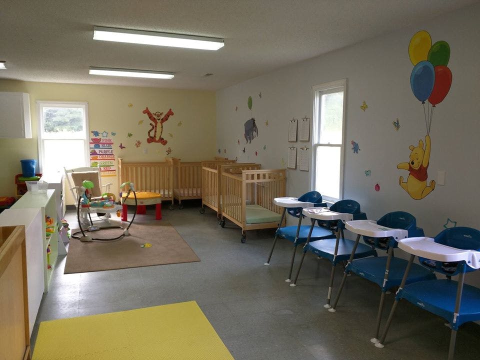 Nursery room with cribs, high chairs, and wall decals