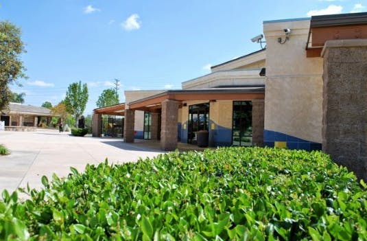Exterior of a building with a covered walkway and green bushes in the foreground
