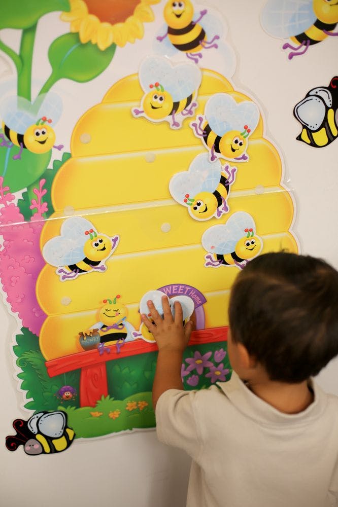 Child touching a bee-themed wall decoration