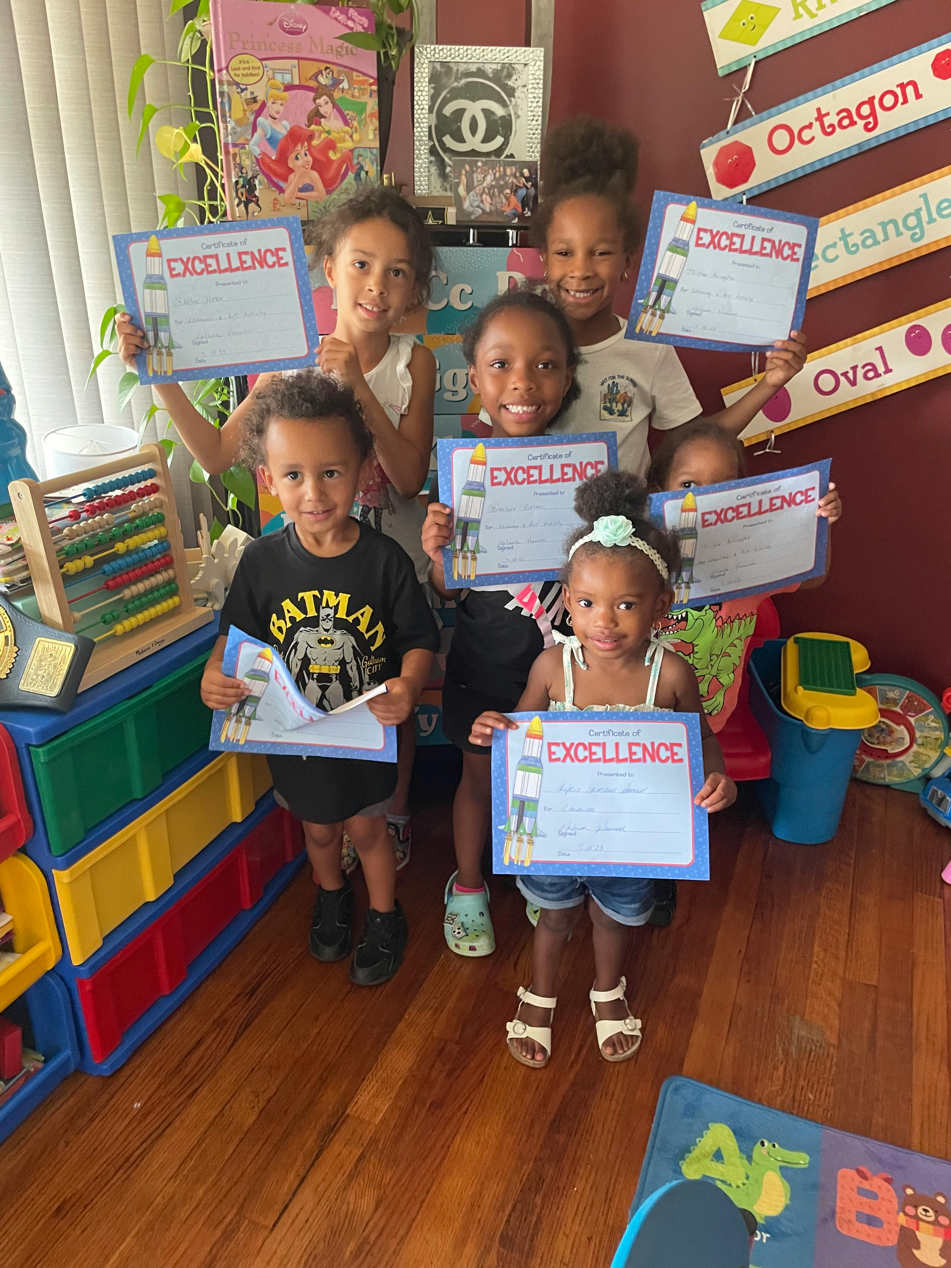 Group of children holding certificates that say "Excellence"