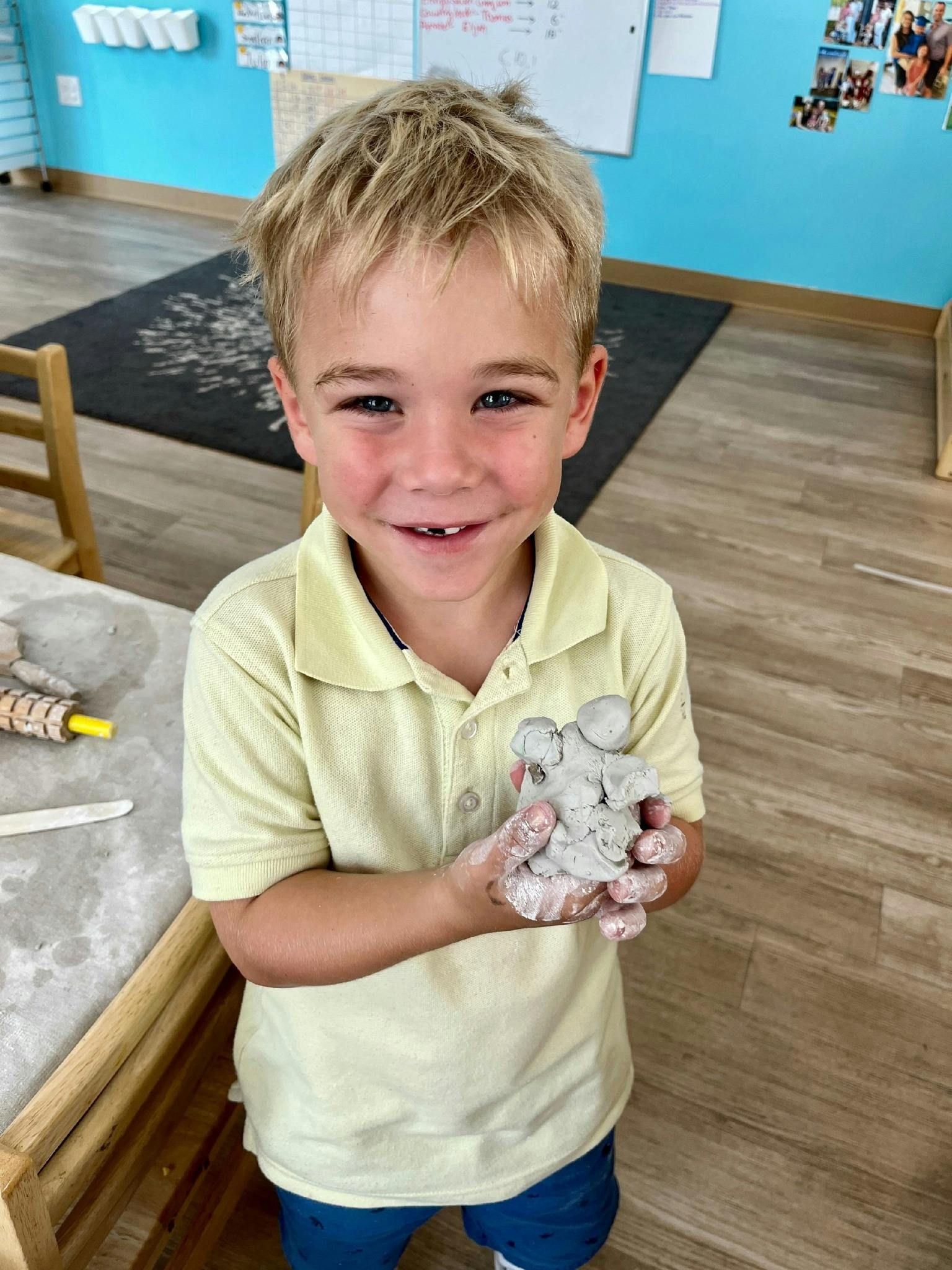 Child holding a small clay sculpture