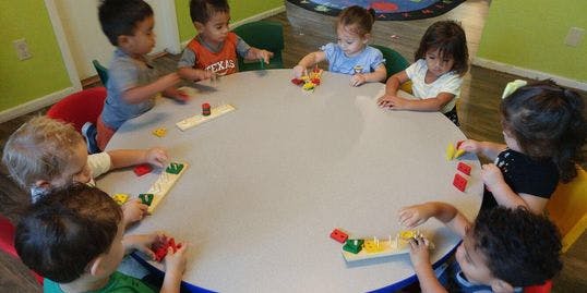 Children playing with colorful blocks at a round table
