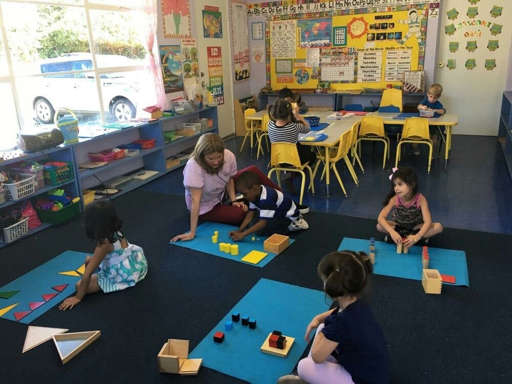 Adult and children on floor with learning materials in a classroom