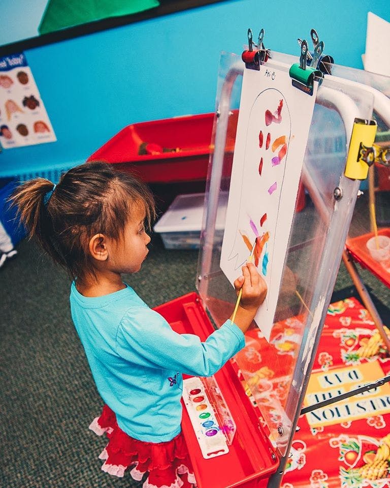 Child painting on an easel in a classroom