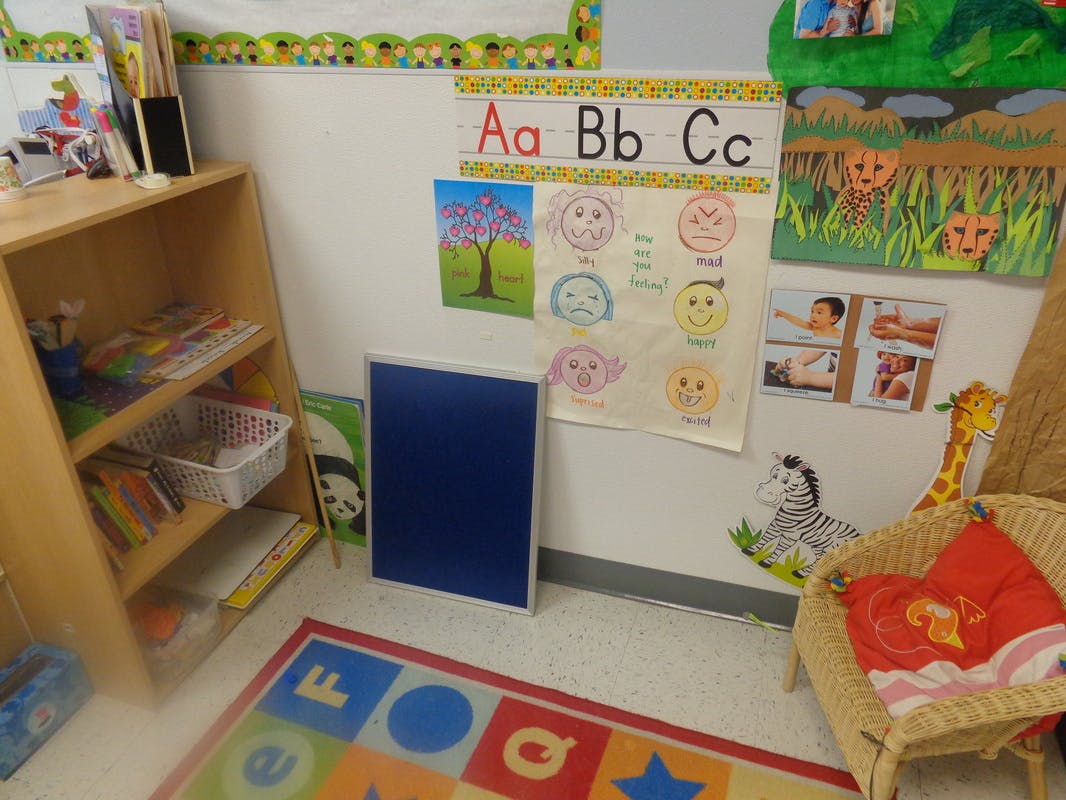 Classroom corner with alphabet chart, bookshelf, and colorful rug