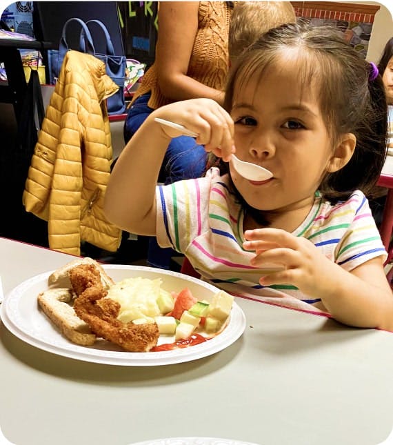 Child eating from a white plate with a spoon