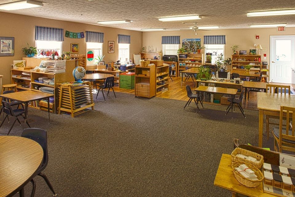 Classroom with tables, chairs, and shelves with shelves of learning materials