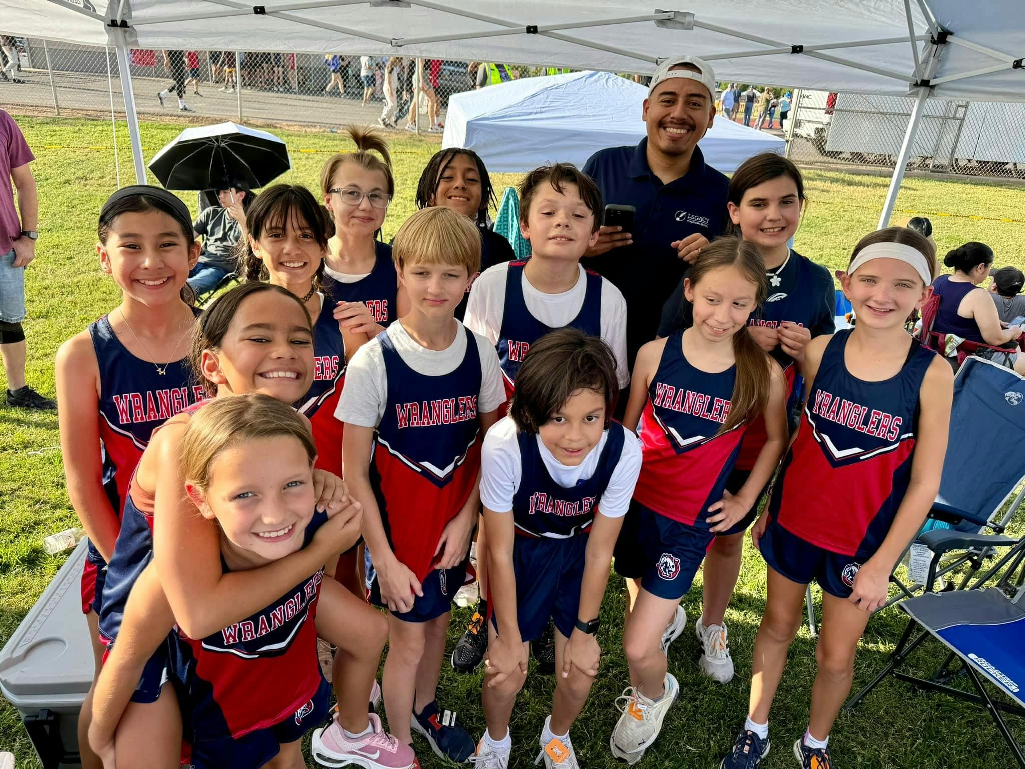 Group of children and adults in athletic uniforms posing outdoors