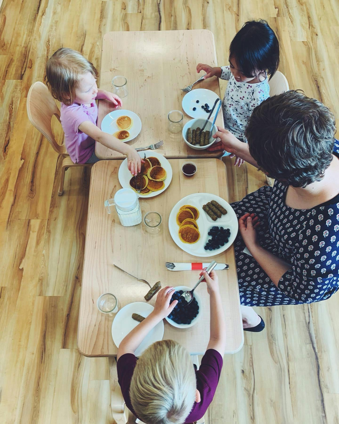 Adult and children eating pancakes and other food at a table
