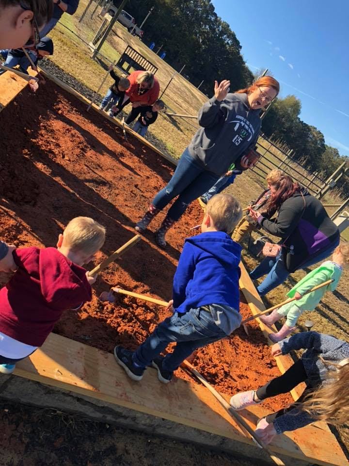 Adults and children working together in a garden bed