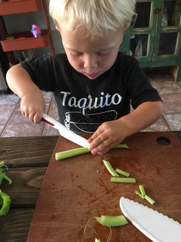 Child cutting celery on a wooden cutting board