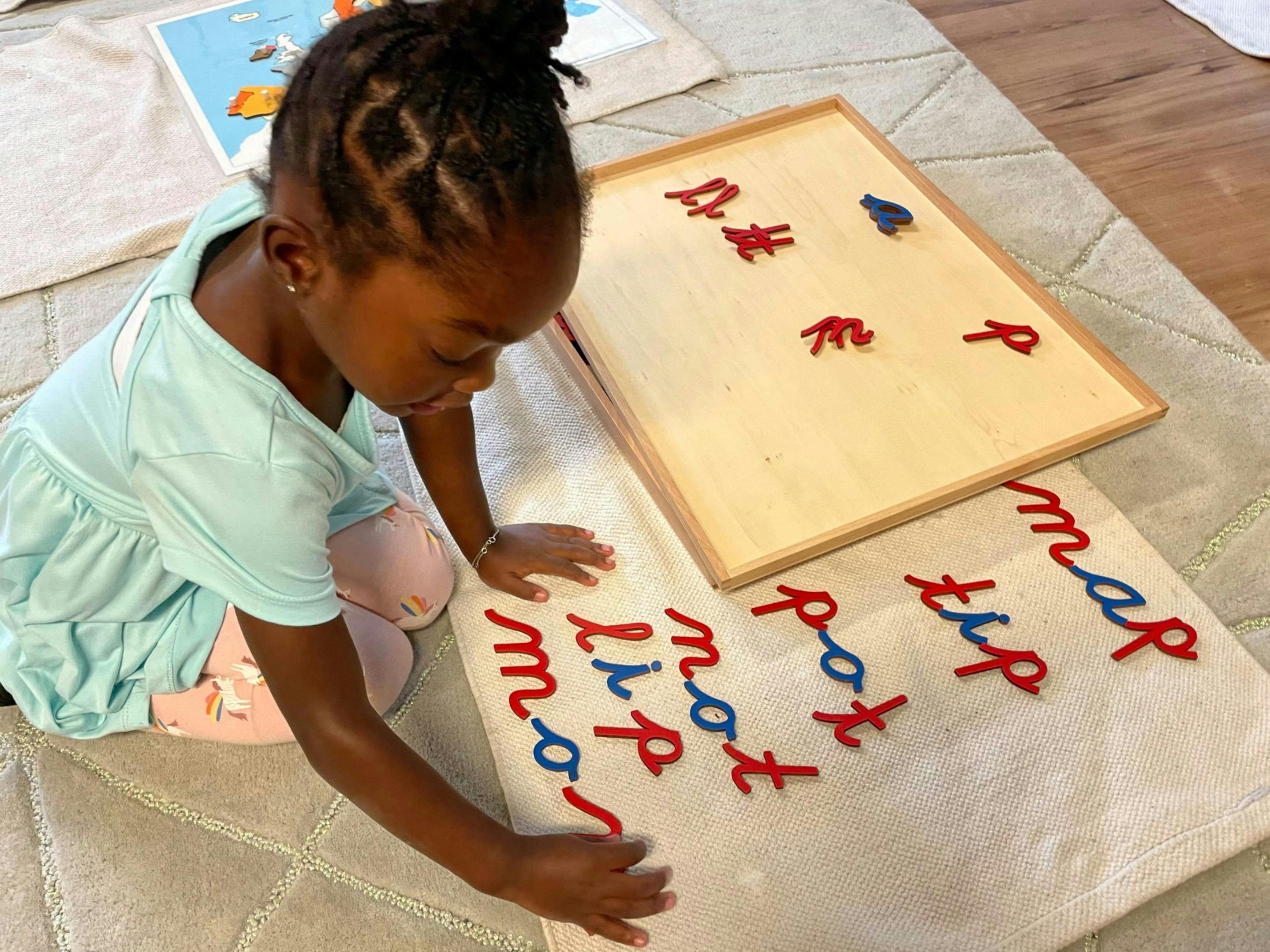 Child on floor learning to spell words with letter cutouts