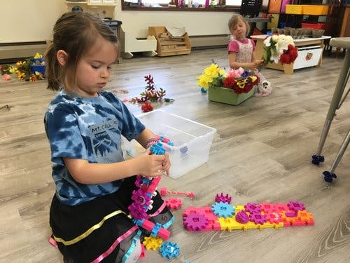Child playing with colorful interlocking toys on the floor