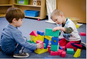 Two children playing with colorful building blocks