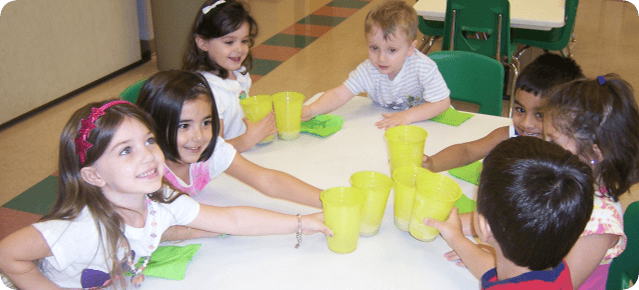 Children sitting around a table with yellow cups