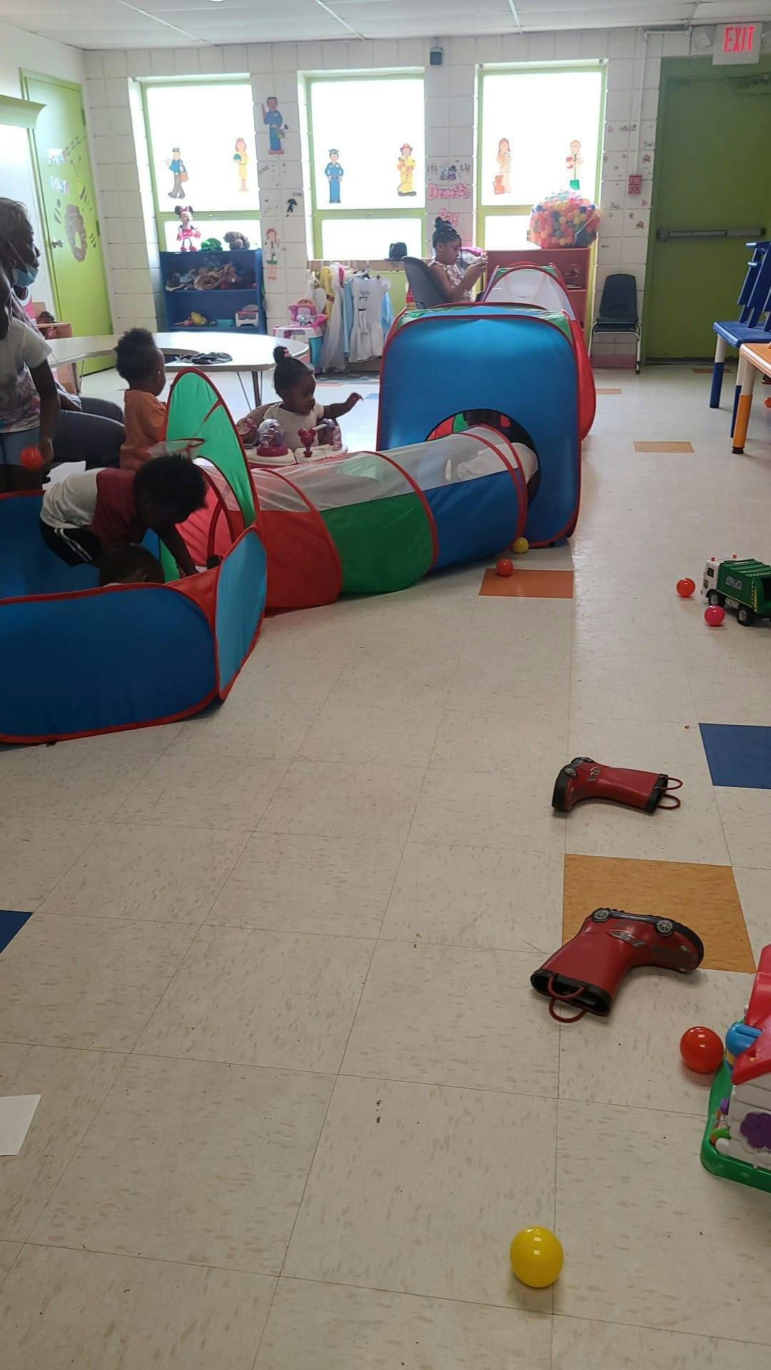 Children playing in a colorful tunnel and tent structure in a classroom