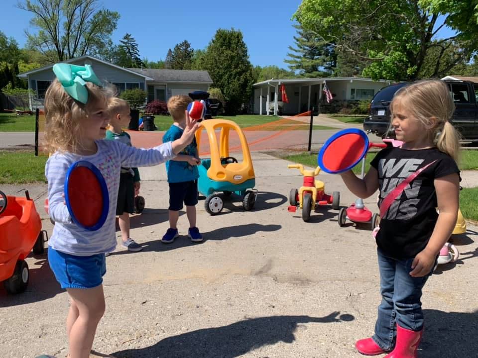 Two children playing with paddle and ball toys outdoors