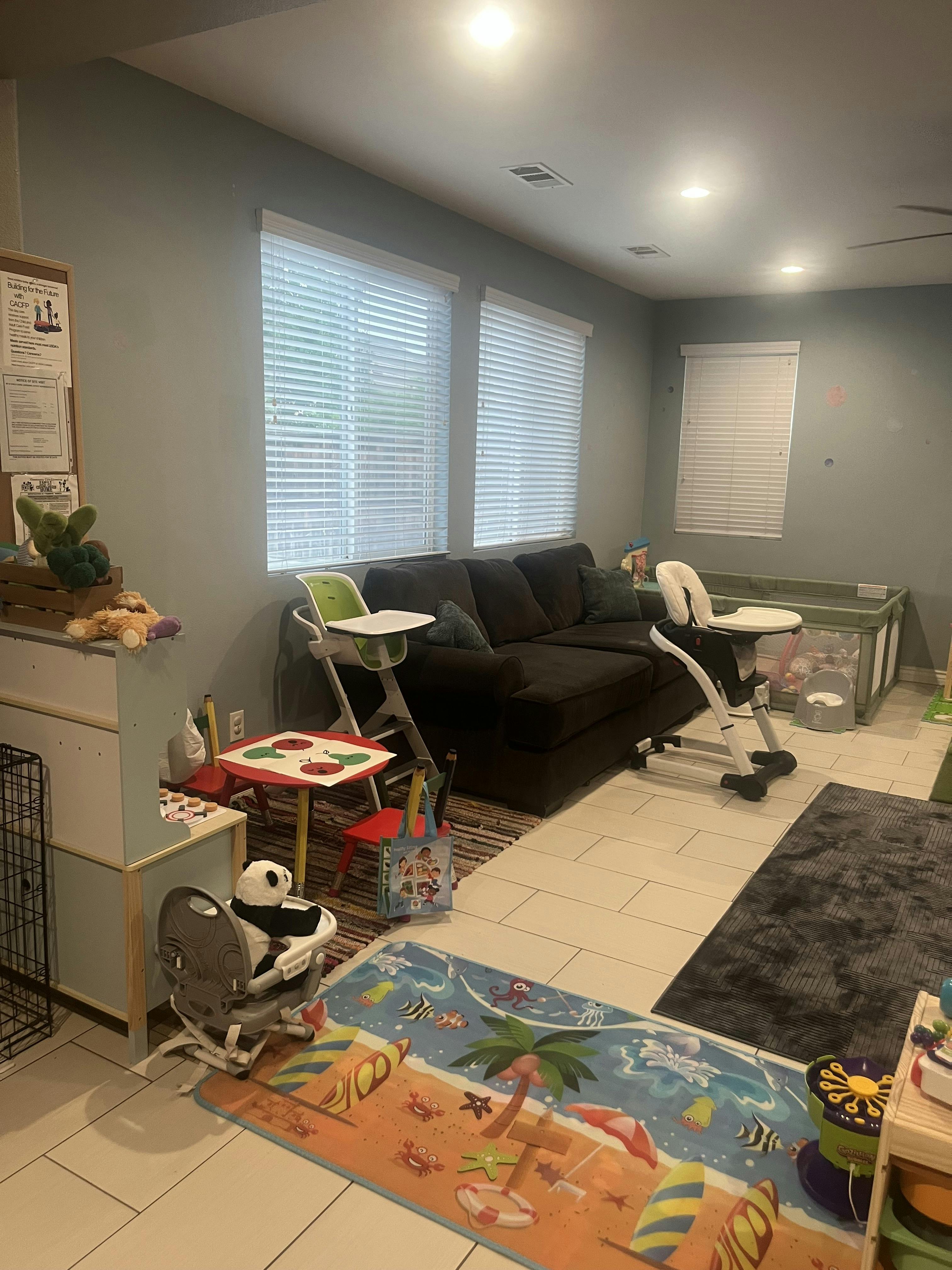 Living room with a dark sofa, two high chairs, and a child's play table