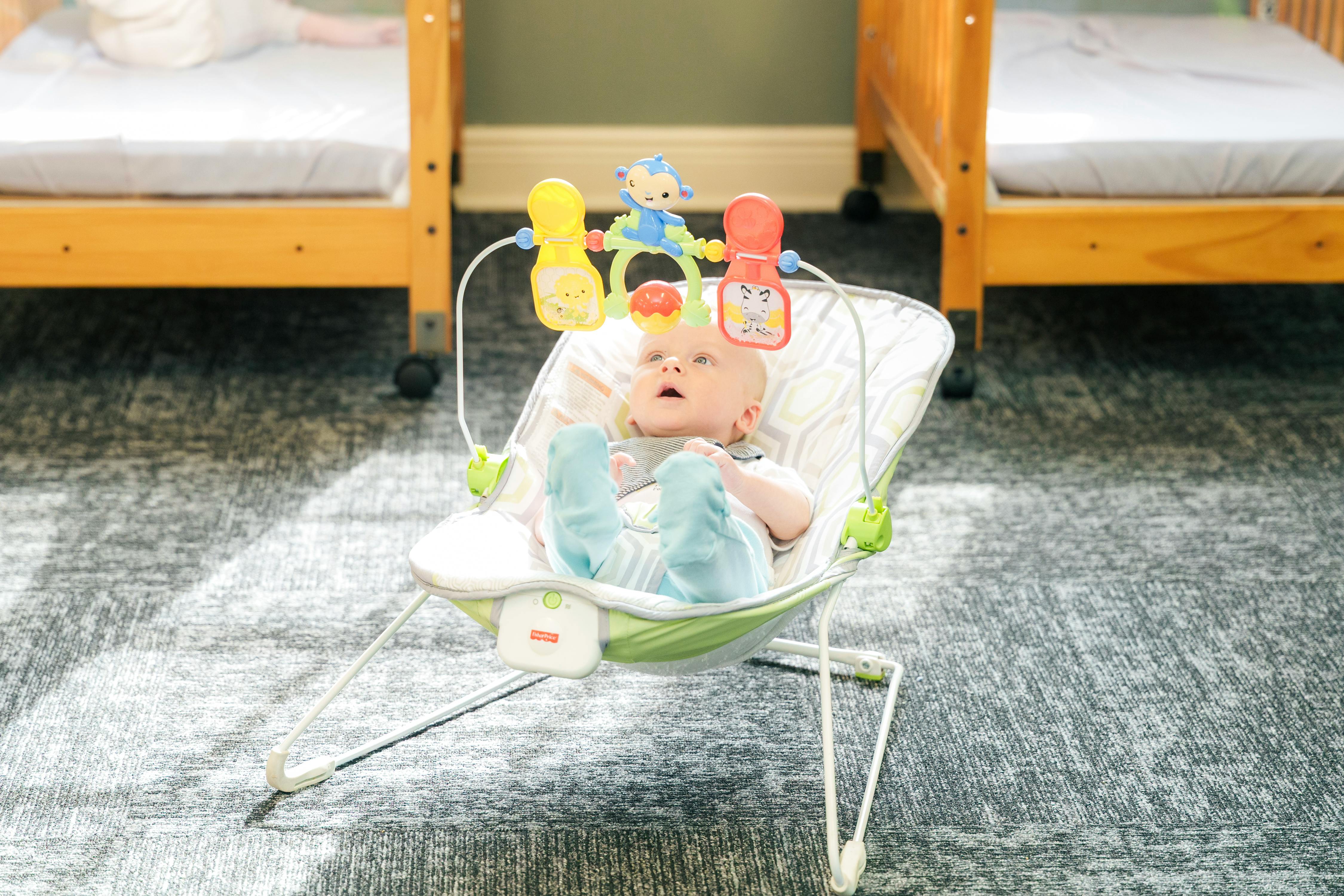 Child in a baby bouncer with toys