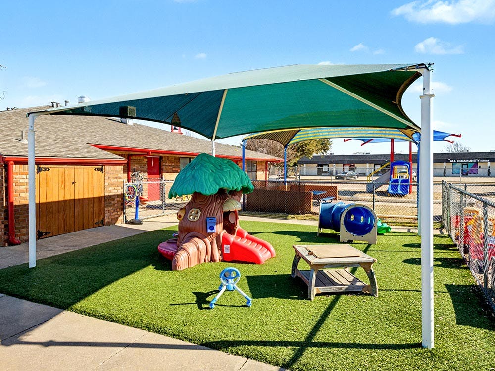 Playground with artificial turf, shade covers, play structure, and tunnel
