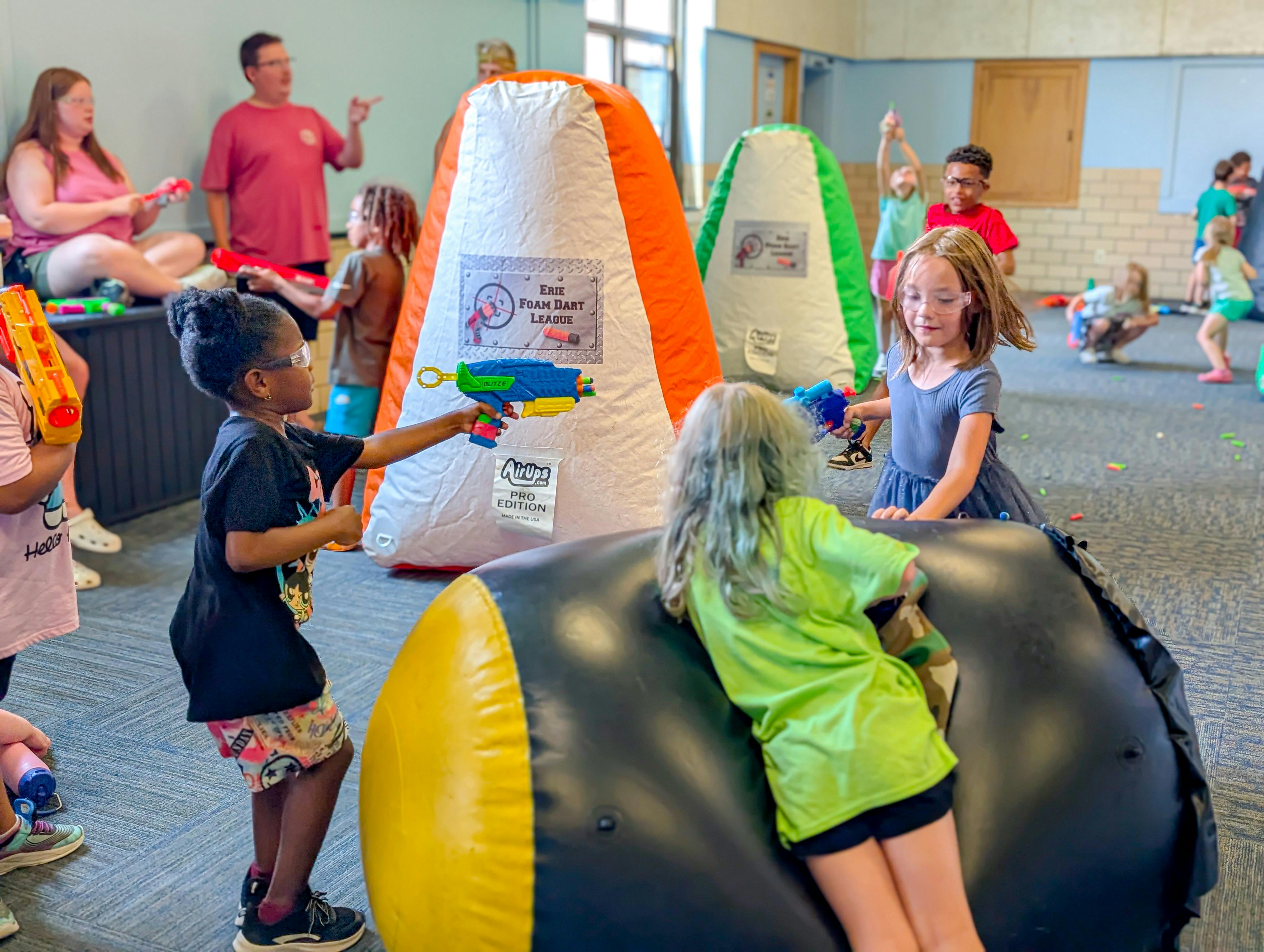 Children playing with toy blasters around inflatable obstacles