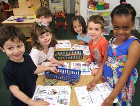Children coloring at a table in a classroom