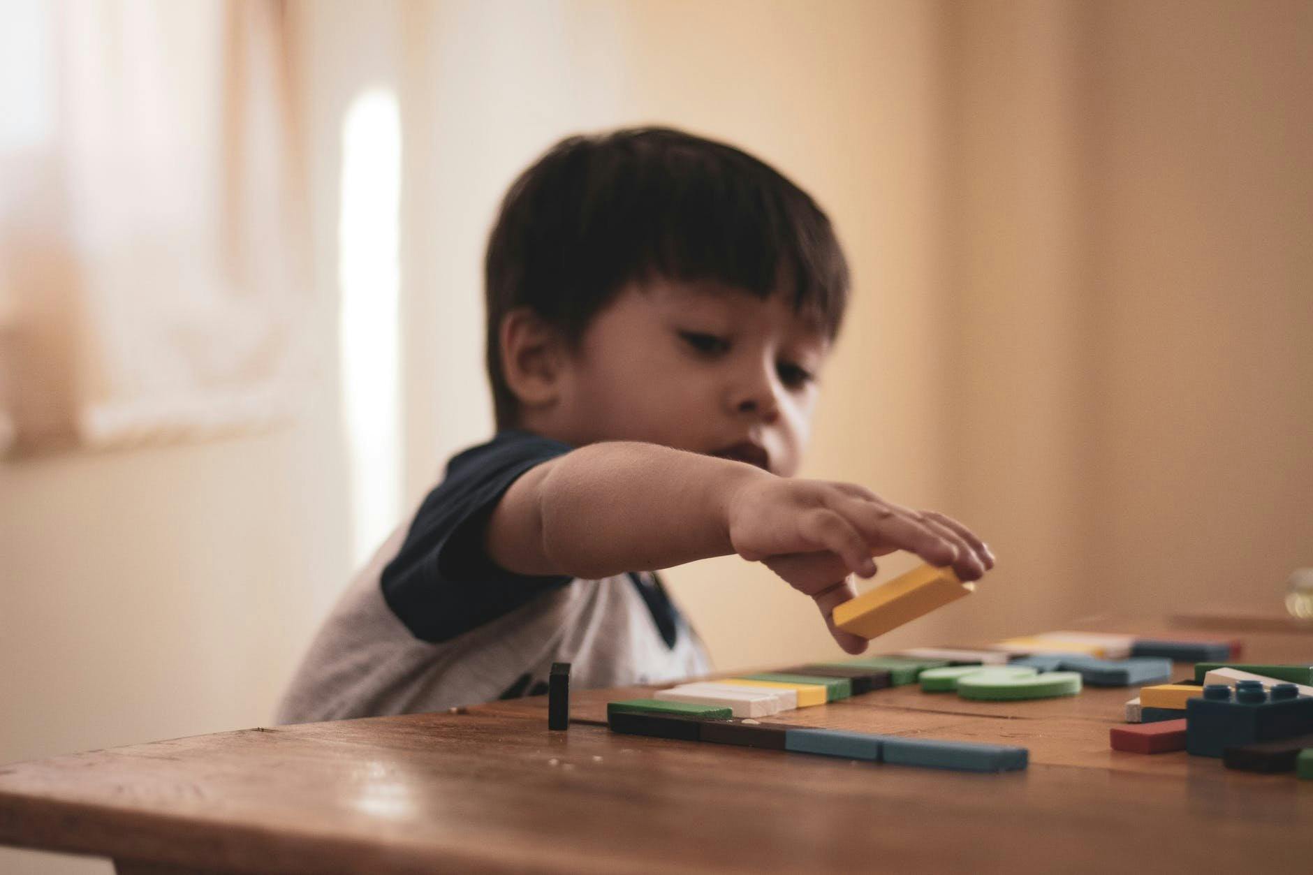 Child playing with colorful building blocks on a wooden table